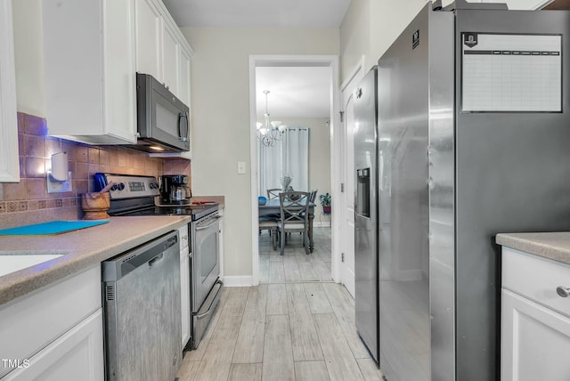 kitchen featuring stainless steel appliances, light wood-style floors, white cabinets, light countertops, and backsplash