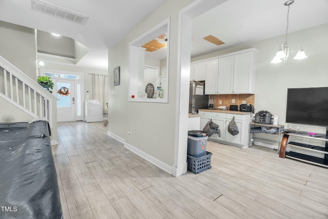 kitchen with wood finish floors, washer / clothes dryer, visible vents, backsplash, and freestanding refrigerator