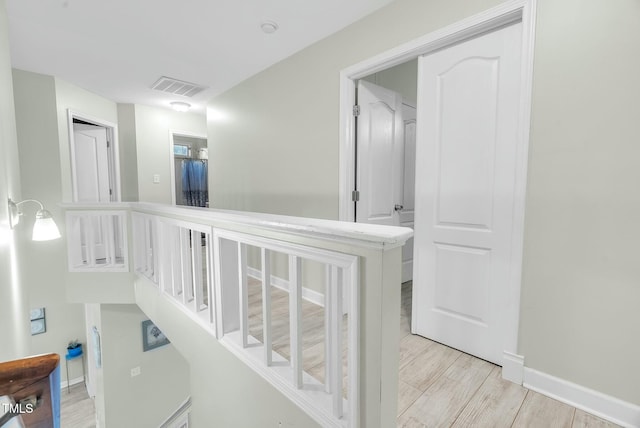 corridor featuring light wood-type flooring, baseboards, and visible vents