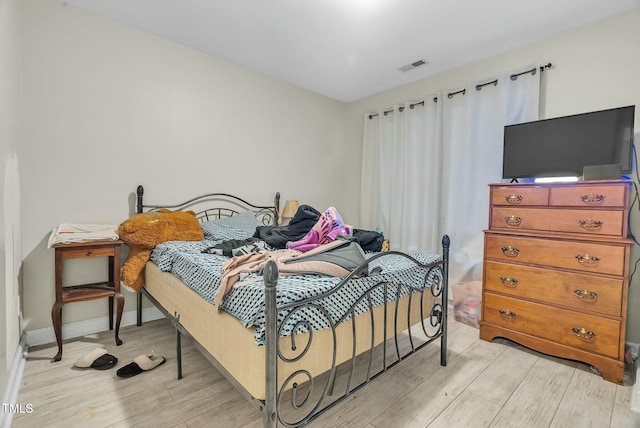 bedroom with light wood finished floors, baseboards, and visible vents