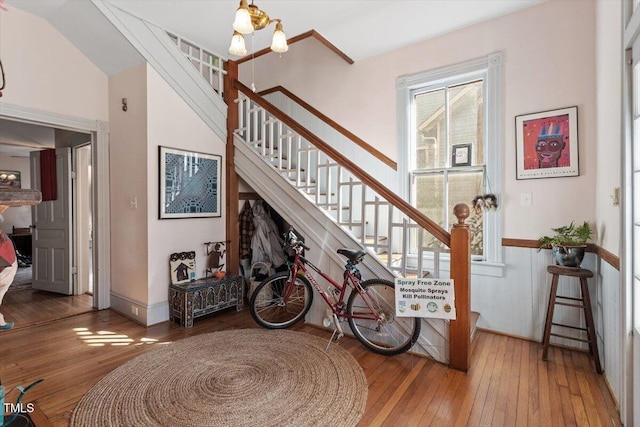 stairway with hardwood / wood-style flooring and an inviting chandelier