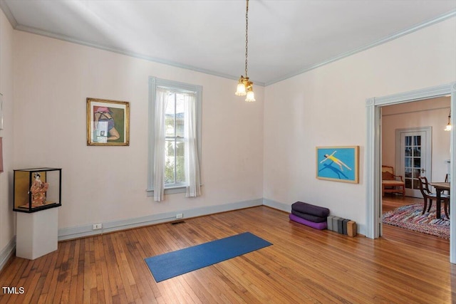 workout area featuring hardwood / wood-style flooring, visible vents, baseboards, and crown molding