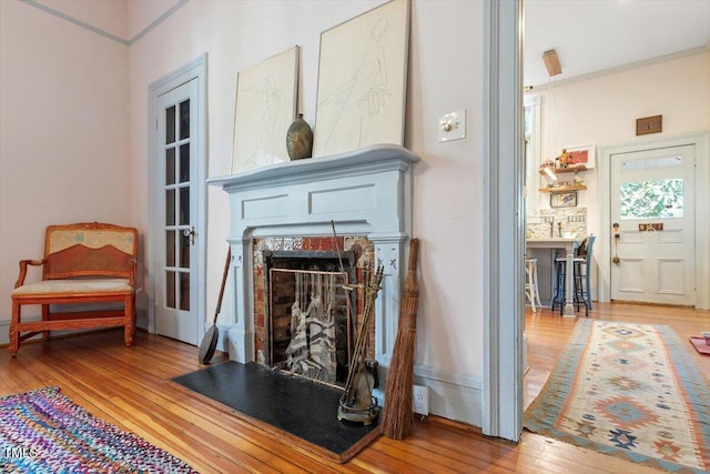 living area with ornamental molding, hardwood / wood-style floors, and a fireplace