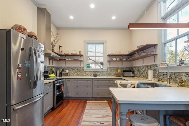 kitchen with appliances with stainless steel finishes, gray cabinets, light countertops, open shelves, and a sink