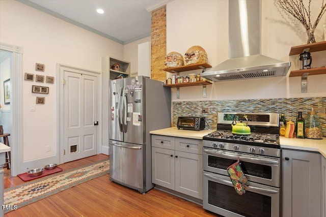 kitchen featuring gray cabinetry, appliances with stainless steel finishes, open shelves, and exhaust hood