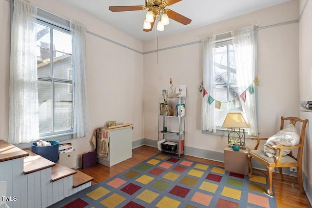 interior space featuring ceiling fan, baseboards, and wood finished floors