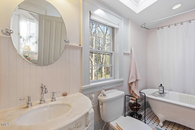 bathroom with vanity, a skylight, a freestanding tub, and toilet