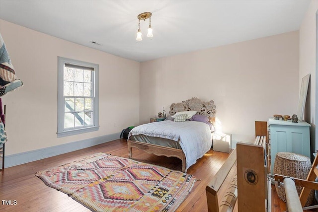 bedroom featuring wood finished floors, visible vents, and baseboards