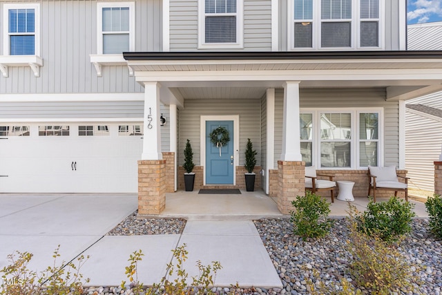 entrance to property with board and batten siding, covered porch, an attached garage, and concrete driveway