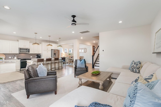 living area featuring light wood finished floors, visible vents, a ceiling fan, stairs, and recessed lighting