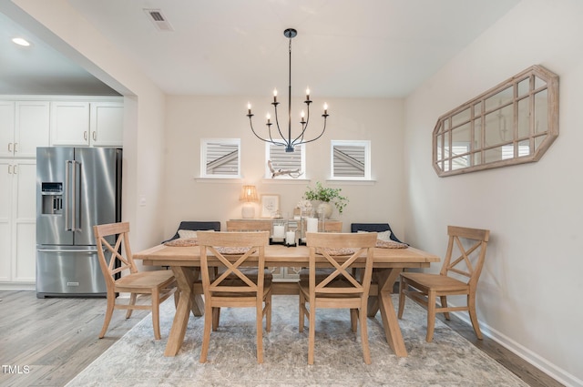 dining area with light wood-style flooring, a notable chandelier, visible vents, baseboards, and breakfast area