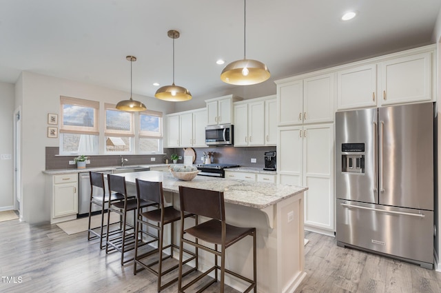 kitchen featuring a kitchen breakfast bar, white cabinets, appliances with stainless steel finishes, decorative backsplash, and a center island