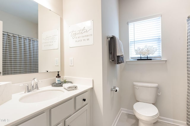 bathroom featuring toilet, baseboards, and vanity