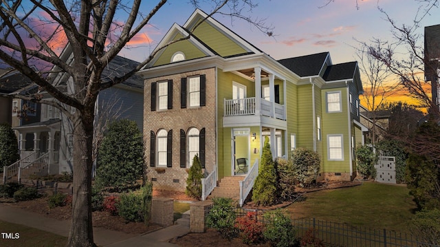 view of front facade with crawl space, brick siding, a yard, and a balcony