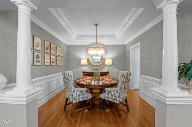 dining space featuring a wainscoted wall, light wood-style flooring, wallpapered walls, and ornate columns