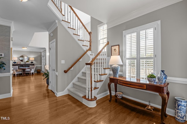 stairway featuring wood finished floors, baseboards, and ornamental molding