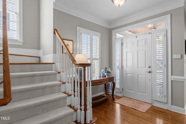 foyer featuring stairway, plenty of natural light, wood finished floors, and crown molding