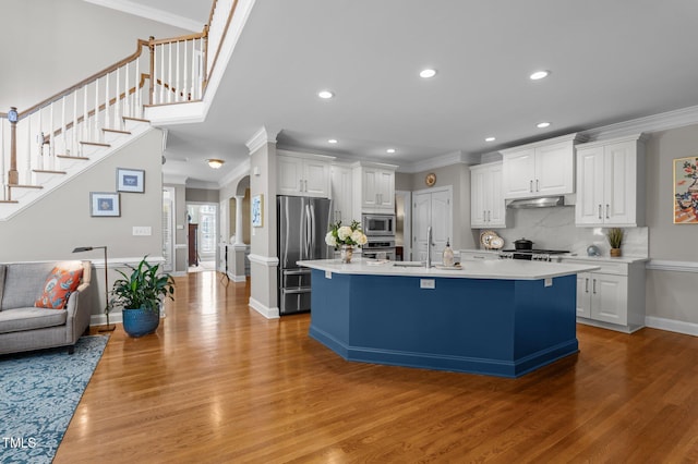 kitchen with under cabinet range hood, white cabinets, appliances with stainless steel finishes, and ornamental molding