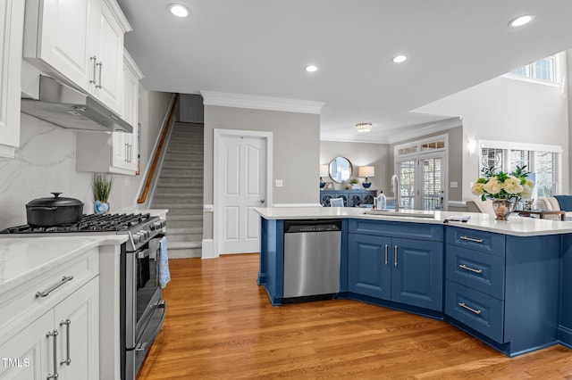 kitchen with a sink, stainless steel appliances, light countertops, white cabinets, and blue cabinets