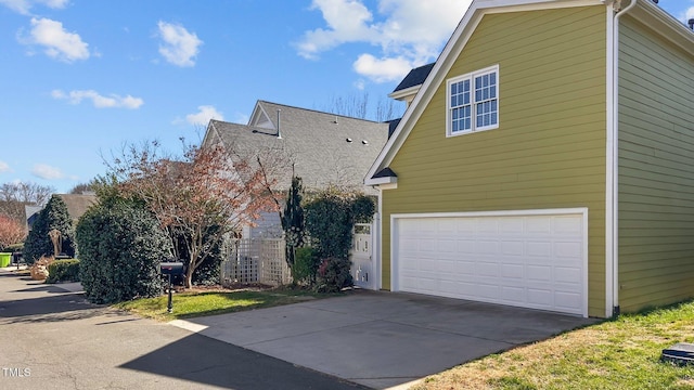 view of side of home featuring concrete driveway and an attached garage