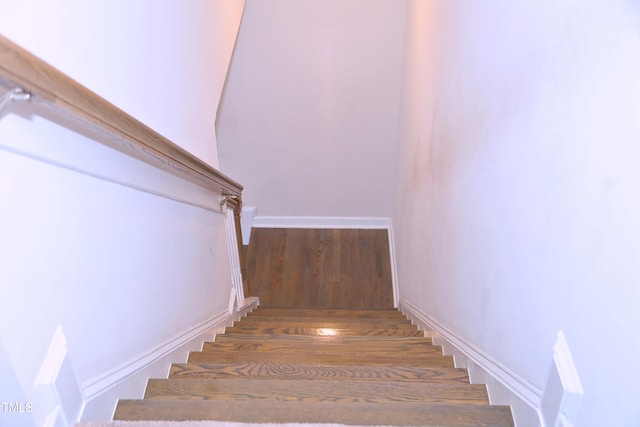 staircase with baseboards and wood finished floors