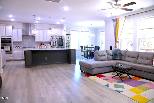 living area with crown molding, recessed lighting, visible vents, light wood-type flooring, and ceiling fan with notable chandelier