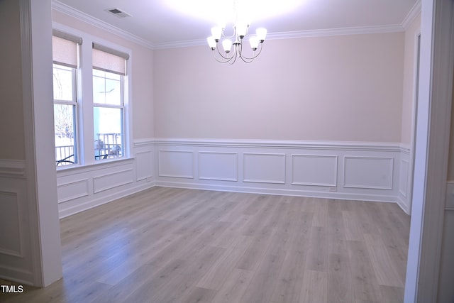 unfurnished room featuring light wood-type flooring, an inviting chandelier, visible vents, and crown molding