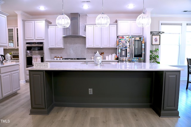 kitchen with visible vents, a large island, wall chimney exhaust hood, stainless steel appliances, and crown molding