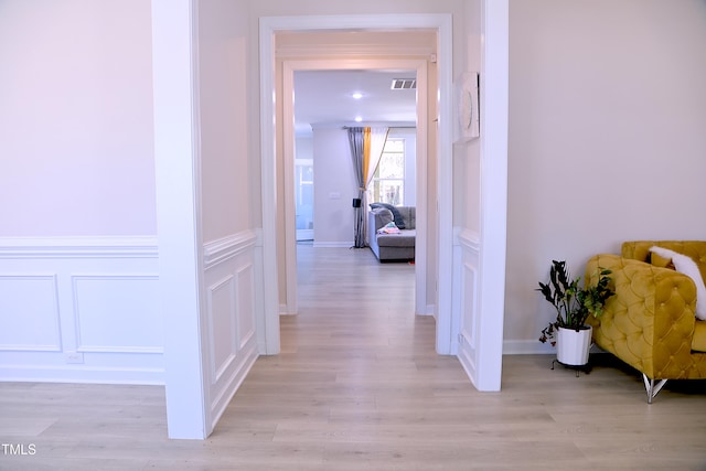 hall with visible vents, a decorative wall, and light wood-style flooring