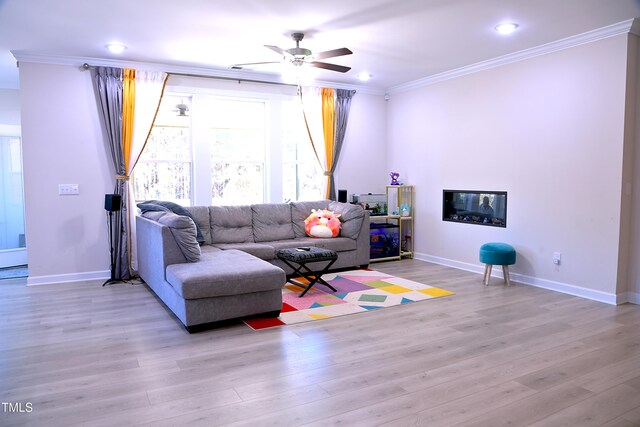 living room with ornamental molding, light wood-style flooring, and baseboards