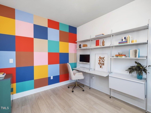 office space featuring built in desk, baseboards, and wood finished floors