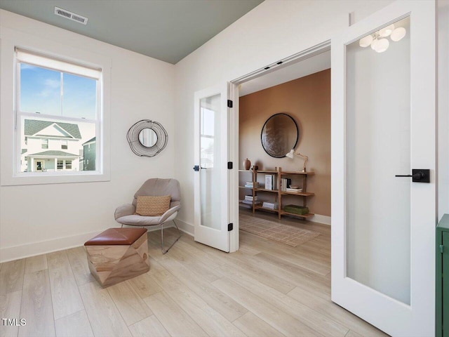 sitting room with french doors, light wood-type flooring, visible vents, and baseboards