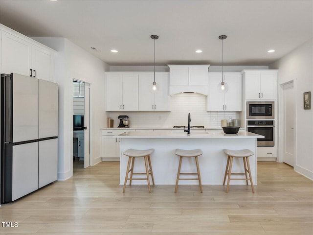 kitchen featuring backsplash, freestanding refrigerator, built in microwave, oven, and premium range hood