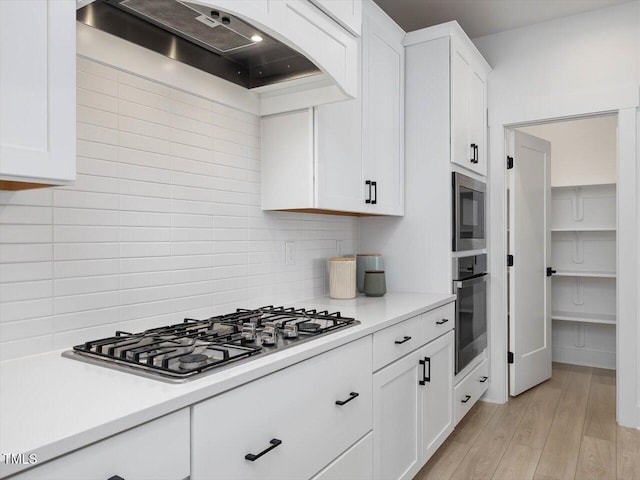 kitchen featuring custom exhaust hood, appliances with stainless steel finishes, light countertops, and backsplash