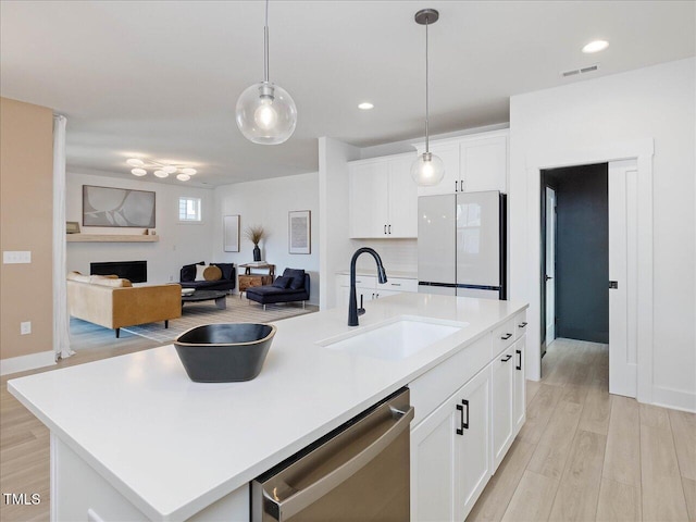 kitchen with a sink, visible vents, open floor plan, freestanding refrigerator, and dishwasher