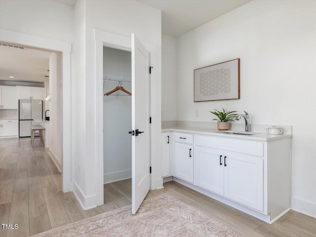 bathroom with visible vents, a sink, baseboards, and wood finished floors