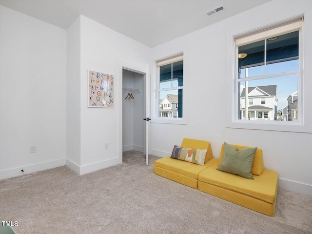 living area featuring carpet floors, visible vents, and baseboards