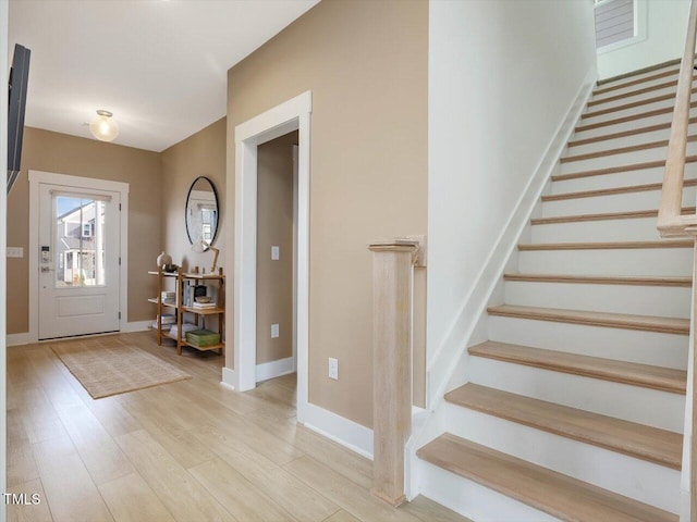 entrance foyer with light wood finished floors, stairs, and baseboards