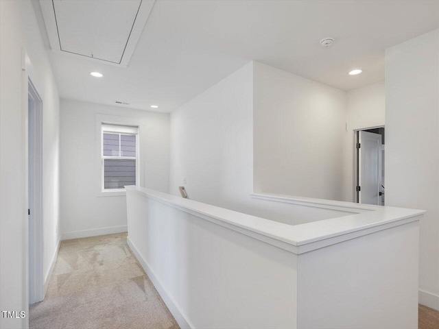 hall with recessed lighting, attic access, light carpet, an upstairs landing, and baseboards