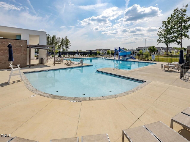 pool featuring fence, a water slide, and a patio