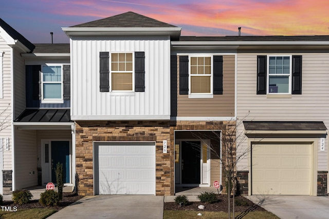 view of property featuring a garage, driveway, metal roof, a standing seam roof, and board and batten siding