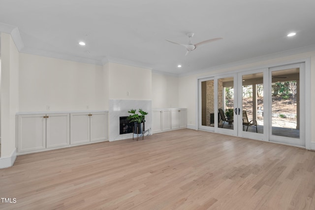 unfurnished living room with ornamental molding, french doors, a fireplace, and light wood-style flooring