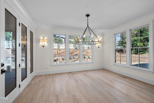 unfurnished dining area featuring baseboards, visible vents, ornamental molding, light wood-type flooring, and a notable chandelier