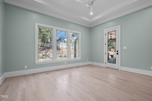 spare room featuring a raised ceiling, visible vents, ceiling fan, wood finished floors, and baseboards