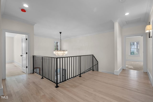 hall with crown molding, baseboards, a chandelier, and light wood-style floors