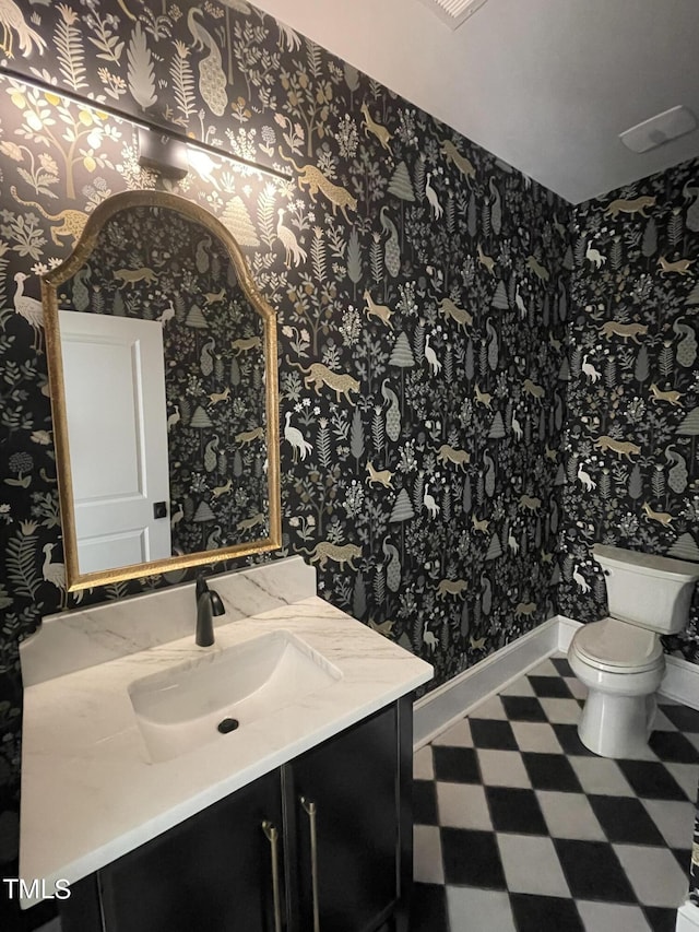 bathroom with toilet, vanity, baseboards, tile patterned floors, and wallpapered walls