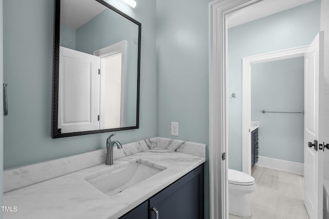 bathroom featuring baseboards, vanity, and toilet