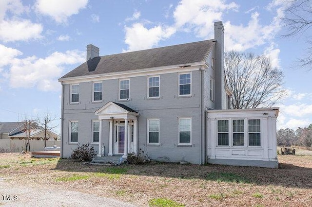 colonial-style house featuring a chimney and fence