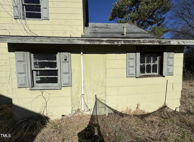 view of property exterior featuring concrete block siding and roof with shingles