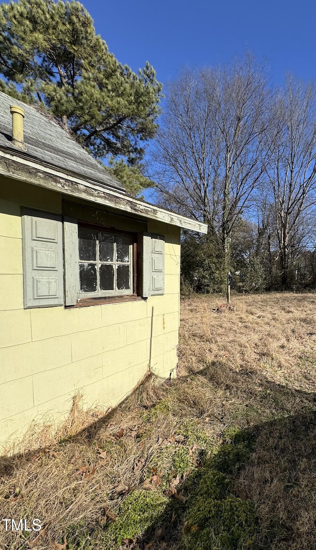 view of side of home featuring roof with shingles and concrete block siding